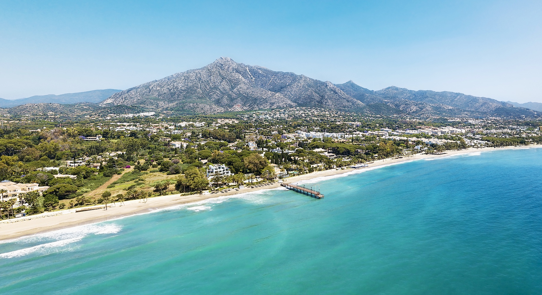 Unique aerial view of luxury and exclusive area in Marbella, golden mile beach, view of Puente Romano Bridge and in background famous La Concha mountain. Emerald water colour