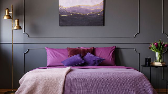 Gold Lamp Next to Purple Bed Against Grey Wall With Molding and Poster in Woman's Bedroom Interior