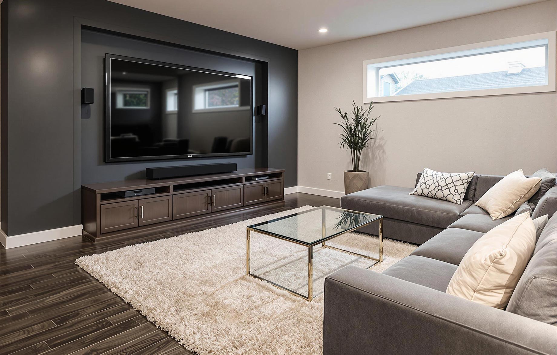 A luxury modern contemporary finished basement featuring a home theater setup with a large flat-screen TV, a comfortable seating area with a sofa and a coffee table, and an egress window. The space is designed to feel like an extension of the upstairs living area, with consistent decor and modern lighting.