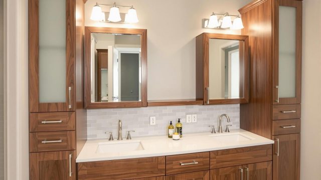 Custom bathroom cabinets with a modern design, featuring a vanity with two sinks, linen towers, wall cabinets, and recessed medicine cabinets. The cabinets are made of solid wood with a sleek finish, soft-close hinges, integrated drawer organizers, and built-in electrical outlets. The bathroom has a stylish and functional layout with a cohesive color scheme.