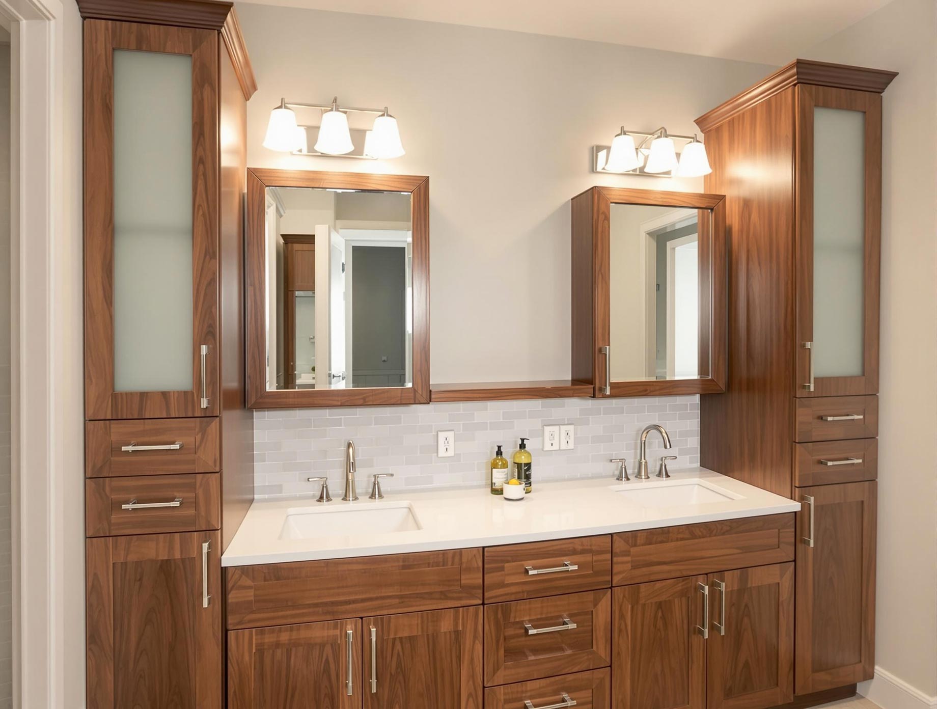 Custom bathroom cabinets with a modern design, featuring a vanity with two sinks, linen towers, wall cabinets, and recessed medicine cabinets. The cabinets are made of solid wood with a sleek finish, soft-close hinges, integrated drawer organizers, and built-in electrical outlets. The bathroom has a stylish and functional layout with a cohesive color scheme.