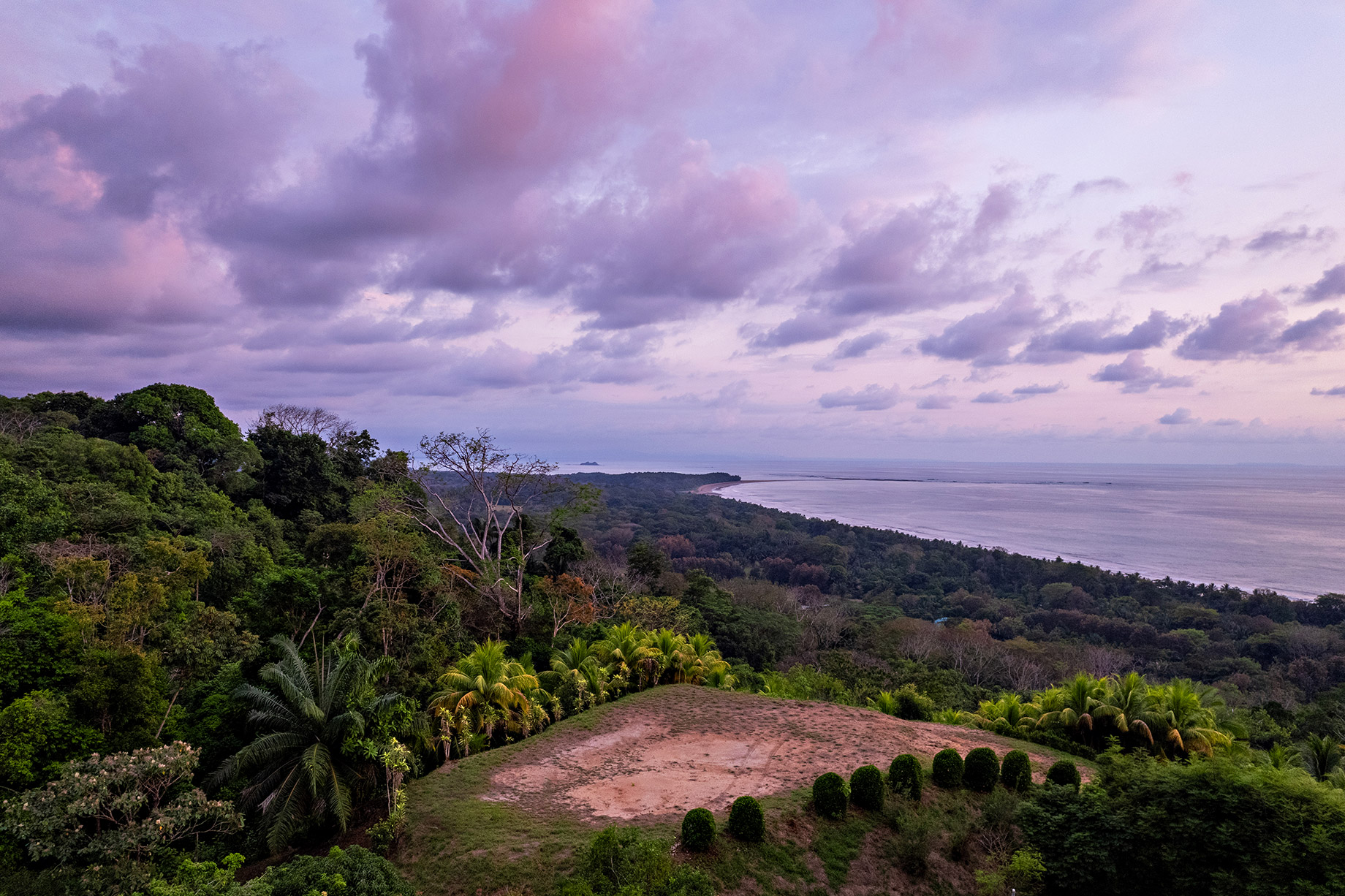 Soft purple and pink clouds over a tropical ridge with panoramic ocean views of Costa Rica’s Whale’s Tail, captured at dusk from the upper building terrace at The Hermosa Estate.