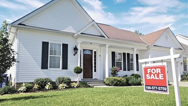 A welcoming suburban home in Charlotte with a 'For Sale' sign in the front yard, well-maintained lawn, and clear blue sky.