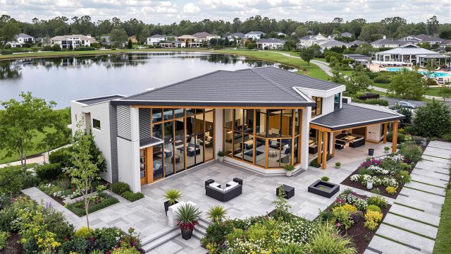 A luxurious house in a gated community surrounded by well-maintained gardens and lush greenery, with a tranquil lake in the background, showcasing modern architecture and high-end finishes.