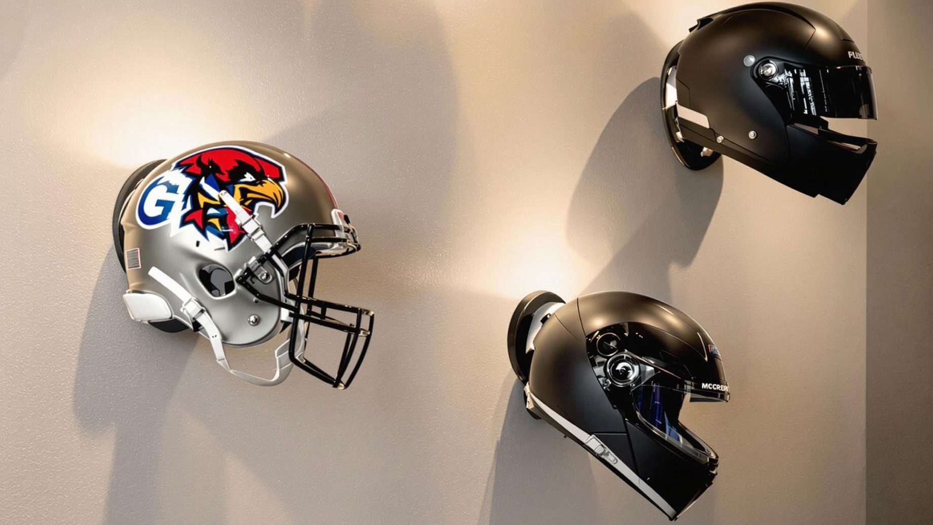 A stylishly decorated wall featuring various helmets mounted as unique decor pieces, including football, motorcycle, and racing helmets, well-lit with soft directional lighting to create a modern and sophisticated gallery effect.