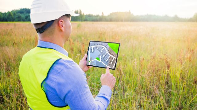 Architect Using a Tablet Surveying a New Residential Housing Building Land Plot