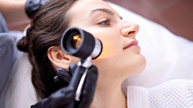 Doctor Dermatologist Examines Skin of a Client's Face