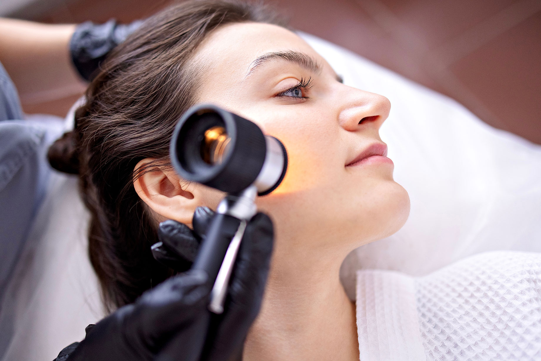 Doctor Dermatologist Examines Skin of a Client's Face