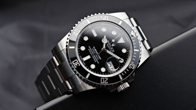 A close-up view of a sophisticated Rolex Submariner watch with a sleek stainless steel band and a black dial, showcasing its timeless design and precision craftsmanship.
