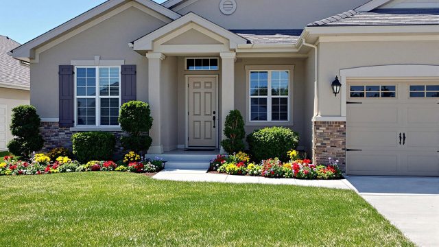 A beautifully maintained house with a well-manicured lawn, modern exterior lighting, and a clean driveway, showcasing enhanced curb appeal on a sunny day.