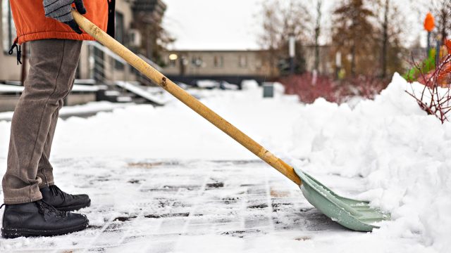 Man Shovelling Snow from Sidewalk in Front of Home