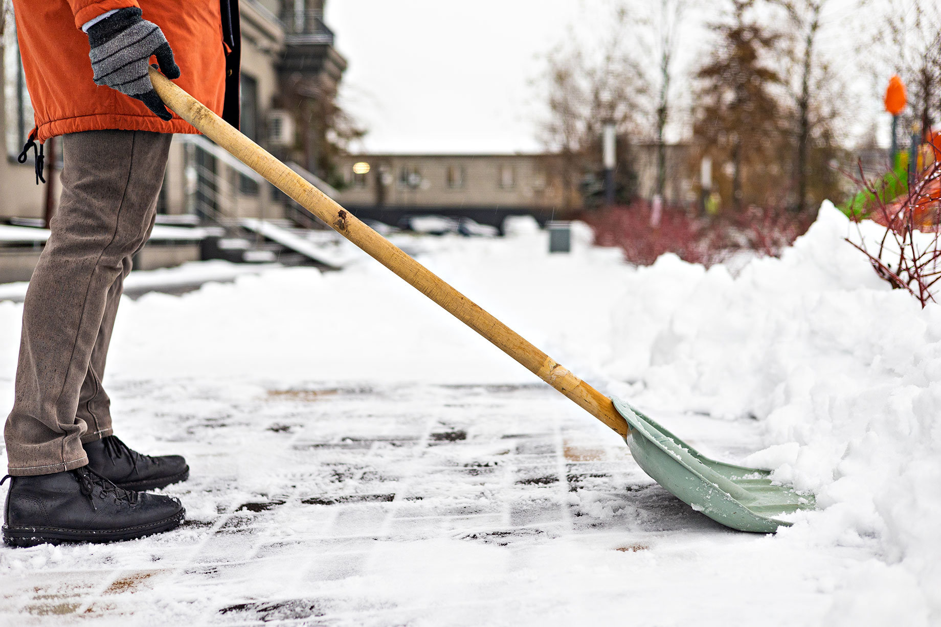 Man Shovelling Snow from Sidewalk in Front of Home