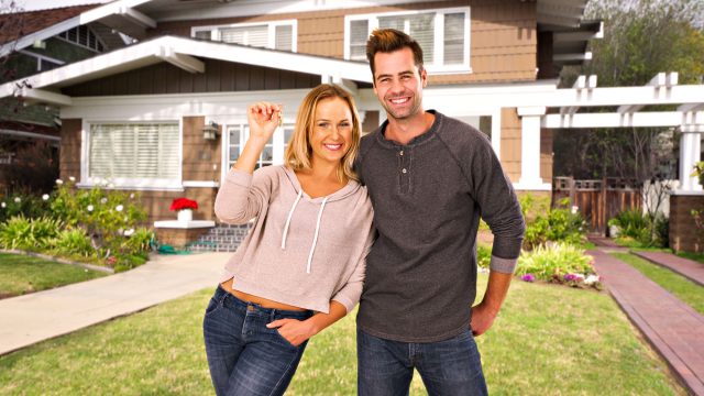 New Homebuyers with Keys in Front of Their New House
