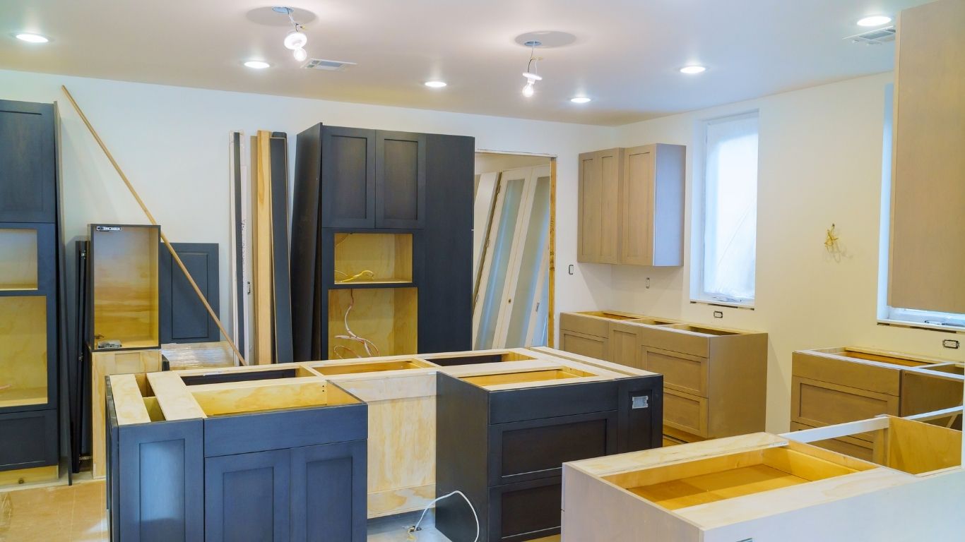 Kitchen under renovation with cabinets being installed, countertops missing, and electrical work in progress.