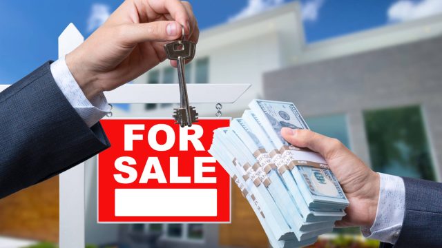 Agent Handing Over Keys of a House for Sale in Exchange for Cash