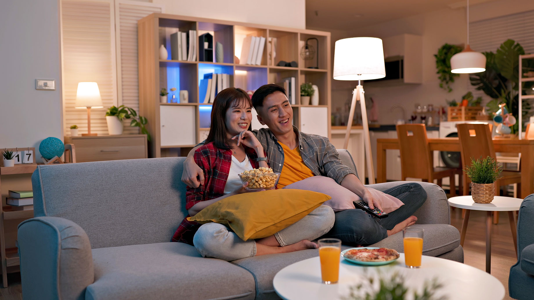 Asian Couple Sitting on a Sofa and Watching TV