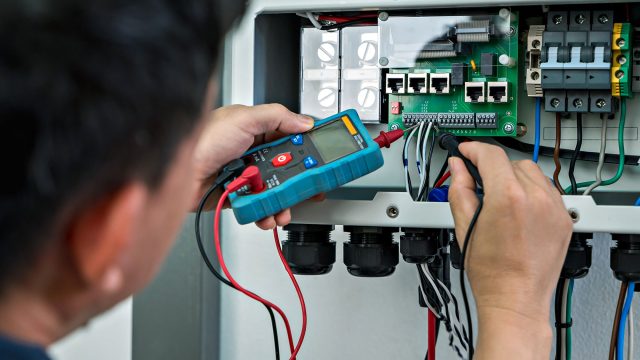 Electrician Checking Voltage From Home Use Solar Cell Combiner Box