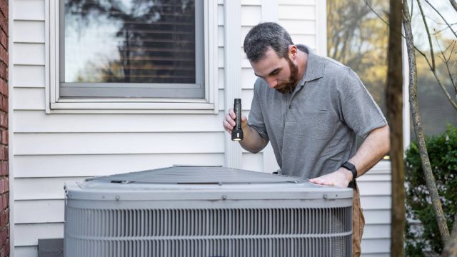 Inspecting HVAC System Outside Home
