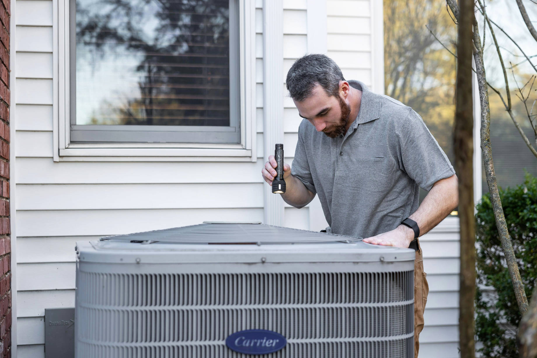 Inspecting HVAC System Outside Home