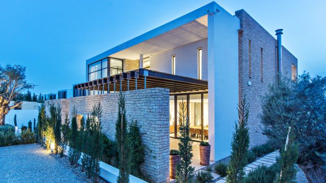 Modern Stone Luxury Villa with a White Facade, Lit Up at Dusk