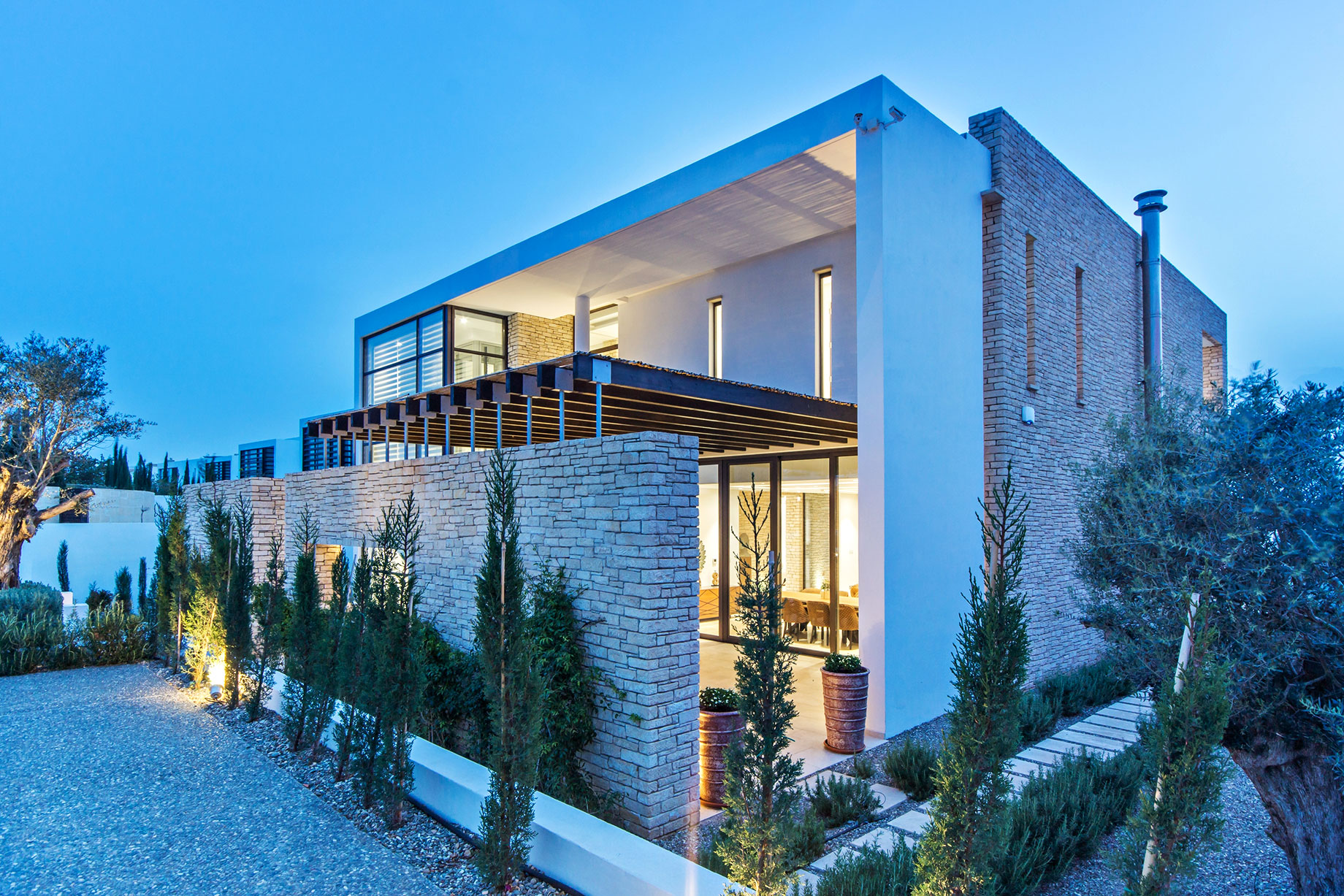 Modern Stone Luxury Villa with a White Facade, Lit Up at Dusk