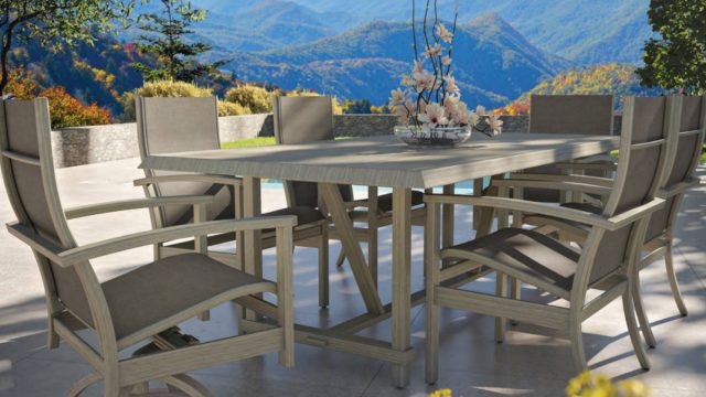 Luxury outdoor rectangular dining table with cushioned armchairs by Castelle, styled on a modern patio with mountain views and a floral centerpiece.)