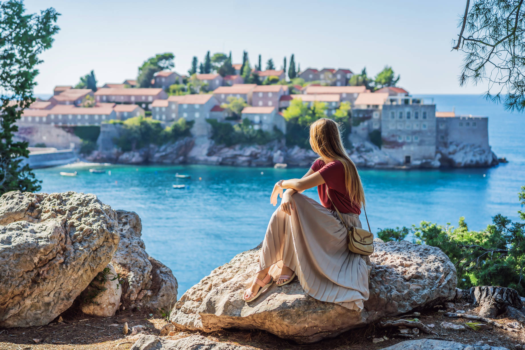 Woman Sitting on a Rock with Views of St. Stephen, Sveti Stefan on the Budva Riviera, Budva, Montenegro