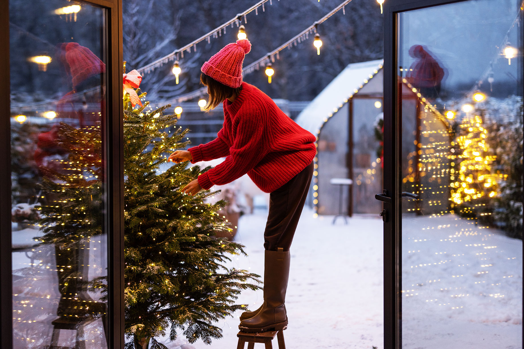 Woman in Red Decorating Backyard Full of Snow for the Christmas Holiday Season