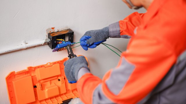 Electrician Carefully Connecting Wires in a Home