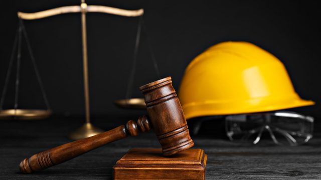 Gavel, Scales, and Construction Worker's Protective Gear on Black Wooden Table