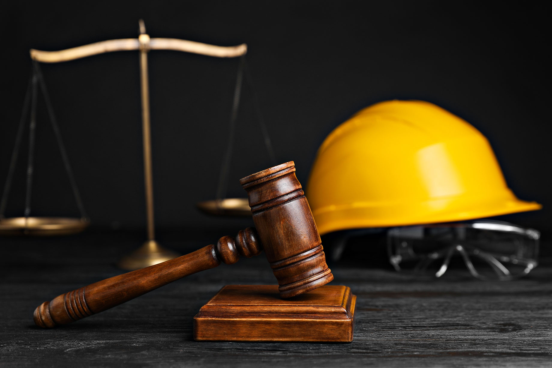 Gavel, Scales, and Construction Worker's Protective Gear on Black Wooden Table