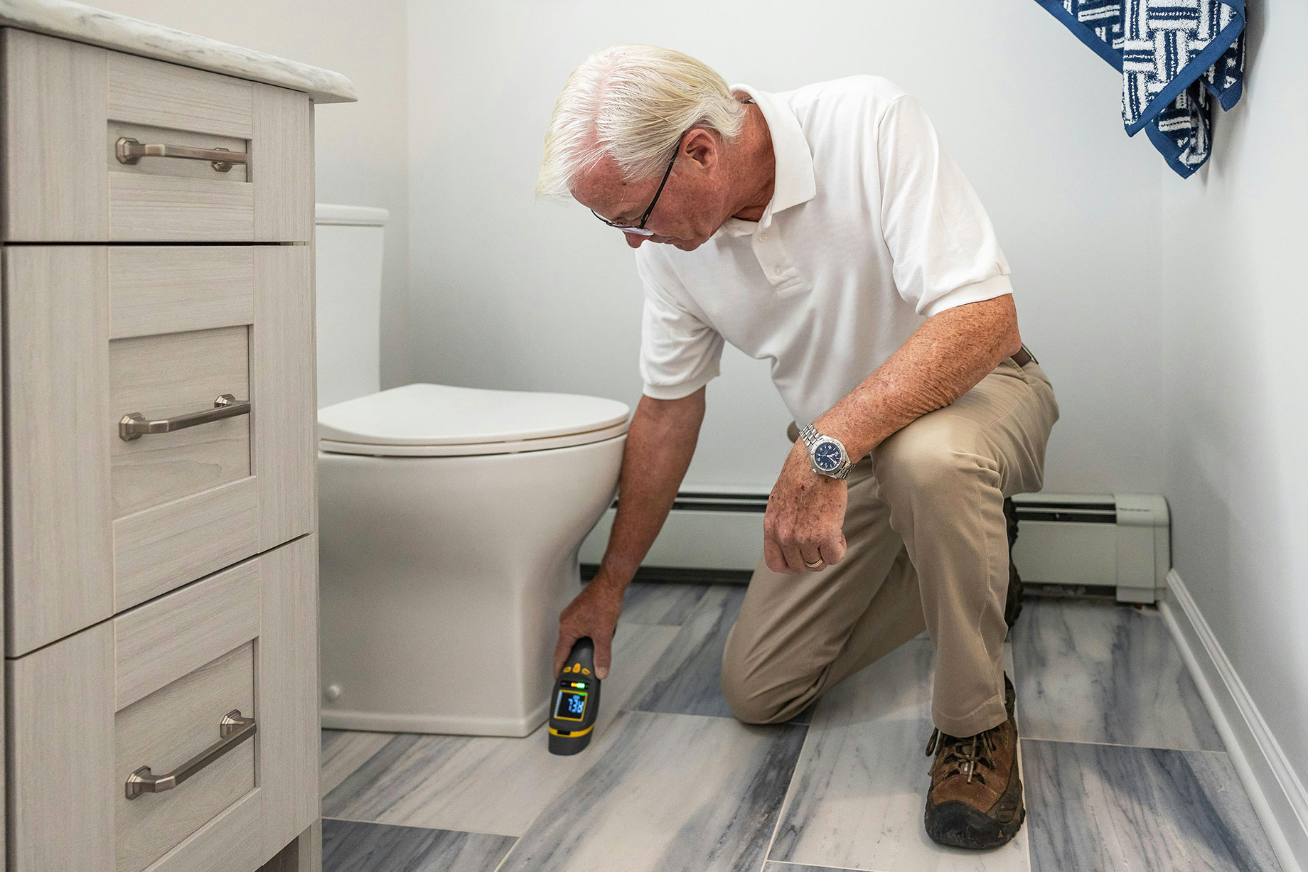 Senior Man Conducting Bathroom Inspection with Device