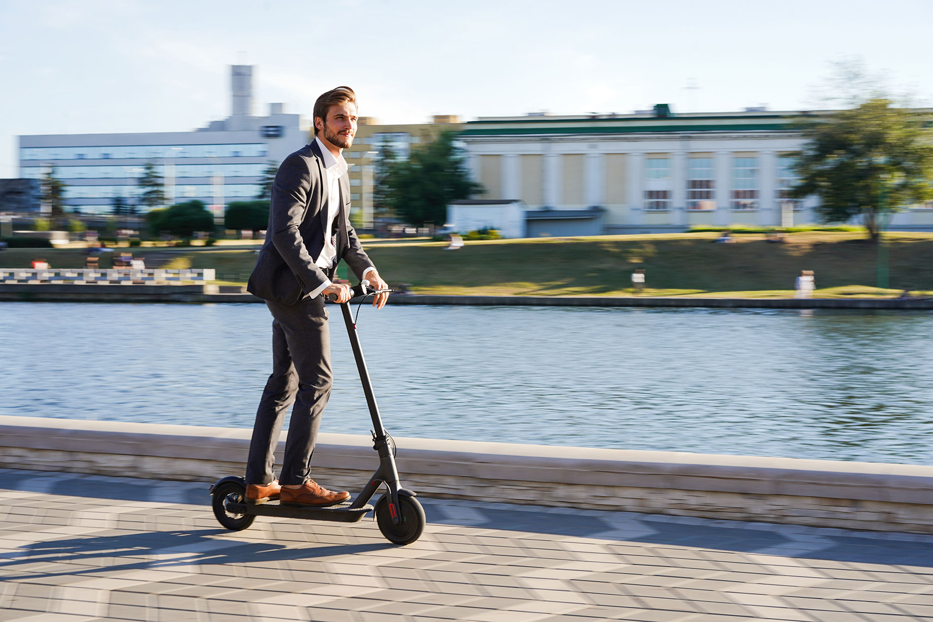 Young Business Man in a Suit Riding an Electric Scooter