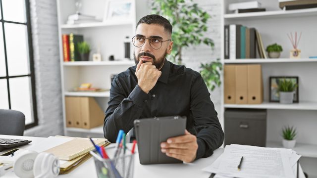 Man Thinking at His Desk with iPad in Hand