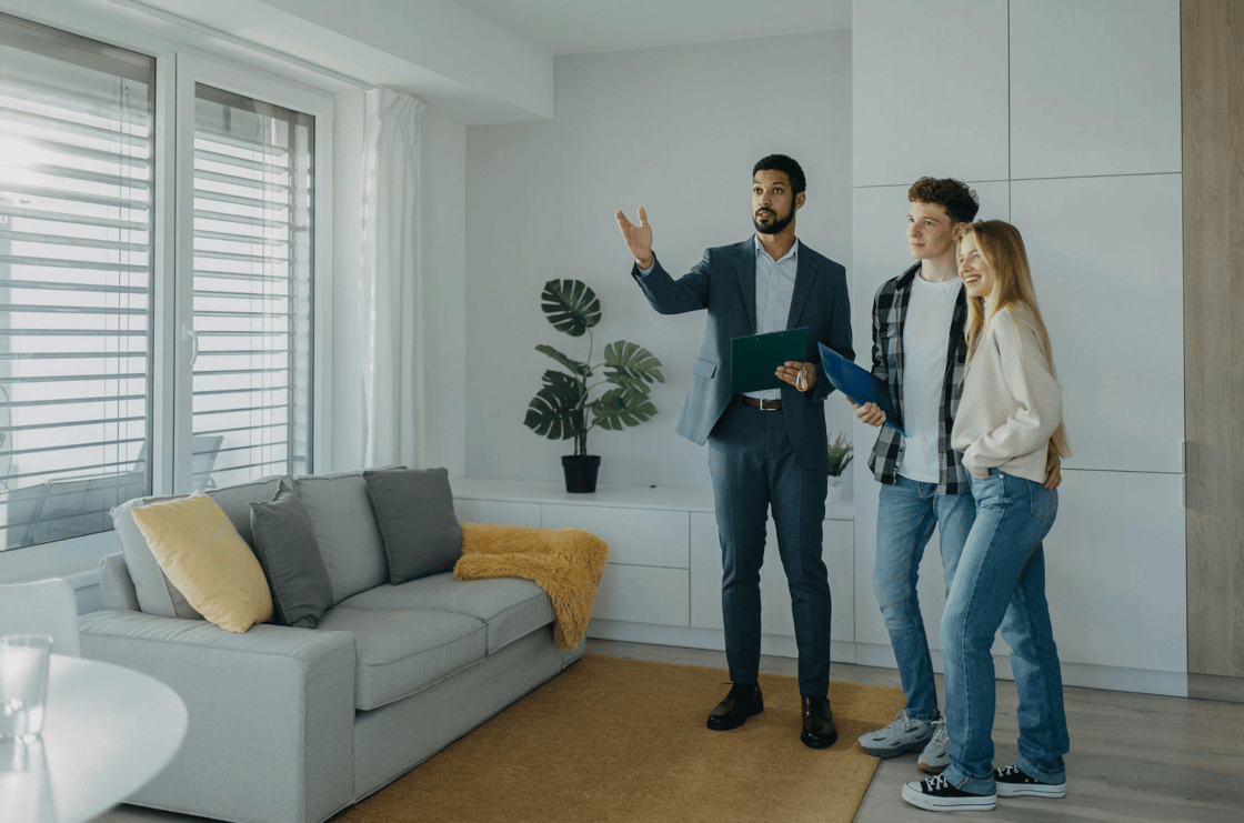 Real estate agent showing modern apartment interior to a smiling young couple.