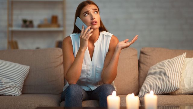 Woman on the Phone with Candles Lit during a Power Outage at Home