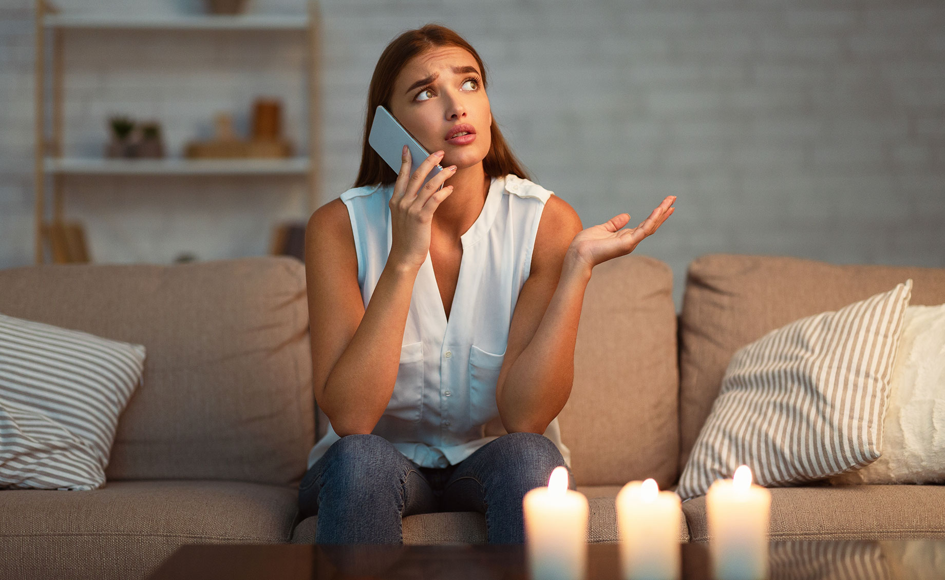Woman on the Phone with Candles Lit during a Power Outage at Home