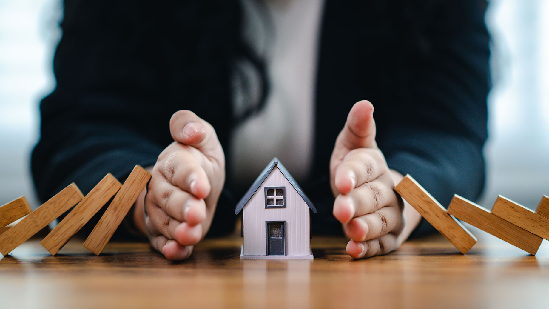 Hands Protecting a House to Illustrate Home Insurance