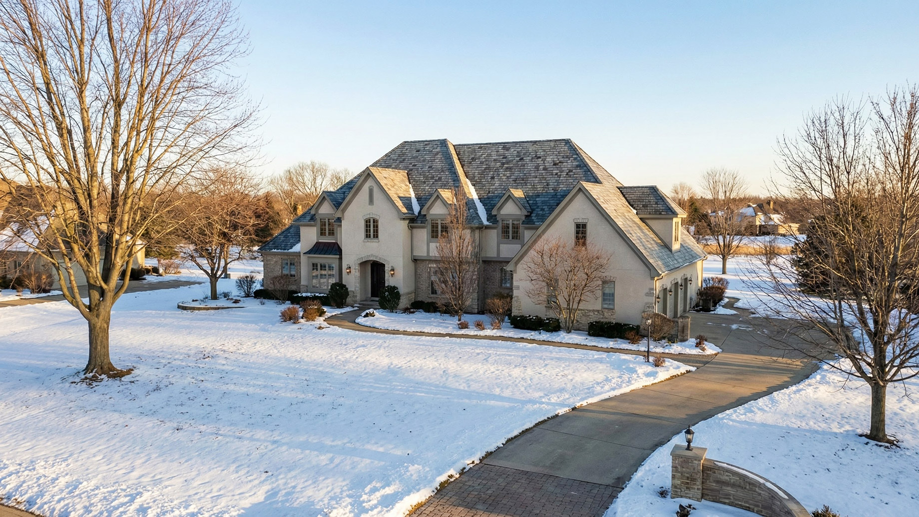 A large, luxury single-family home in DeKalb, Illinois, surrounded by snow, featuring a high-quality roof designed to withstand harsh Northern Illinois winters.