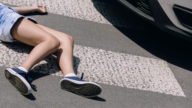 Pedestrian Accident Victim Laying on the Ground Before a Car