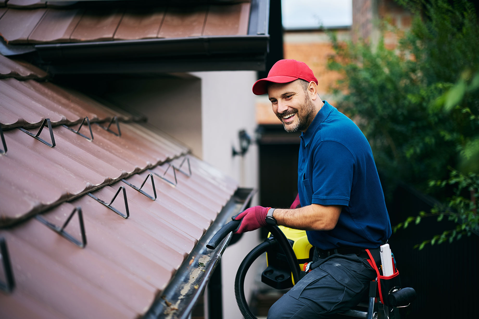 Professional Gutter Maintenance Worker Blowing Leaves Out Of A Gutter