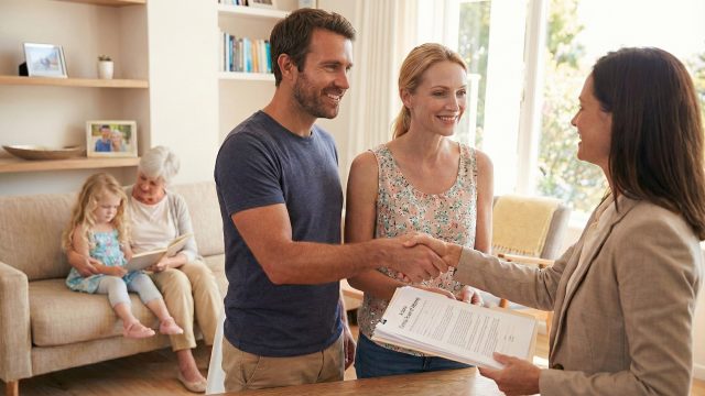 A slim mother in a summer dress and a father stand in a sunny garden with their young daughter, who has long blonde hair, while reviewing a Parental Power of Attorney legal document together.