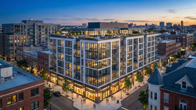 A modern, multi-story urban apartment building at twilight, featuring a rooftop terrace with residents, illuminated units with large windows, and ground-floor retail spaces, situated in a busy city neighborhood with a mix of contemporary and historic architecture.