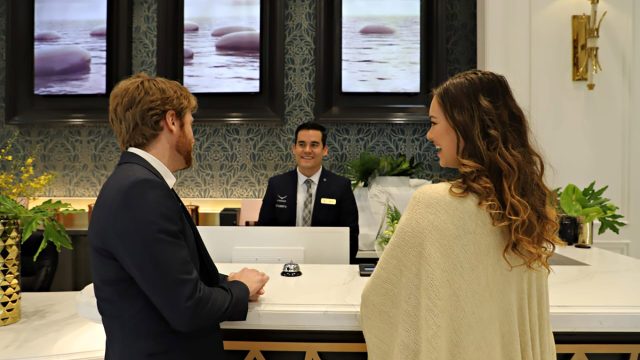 A Condor Security concierge professional engaging warmly with residents at a high-end front desk, illustrating the fusion of premium security and five-star hospitality.