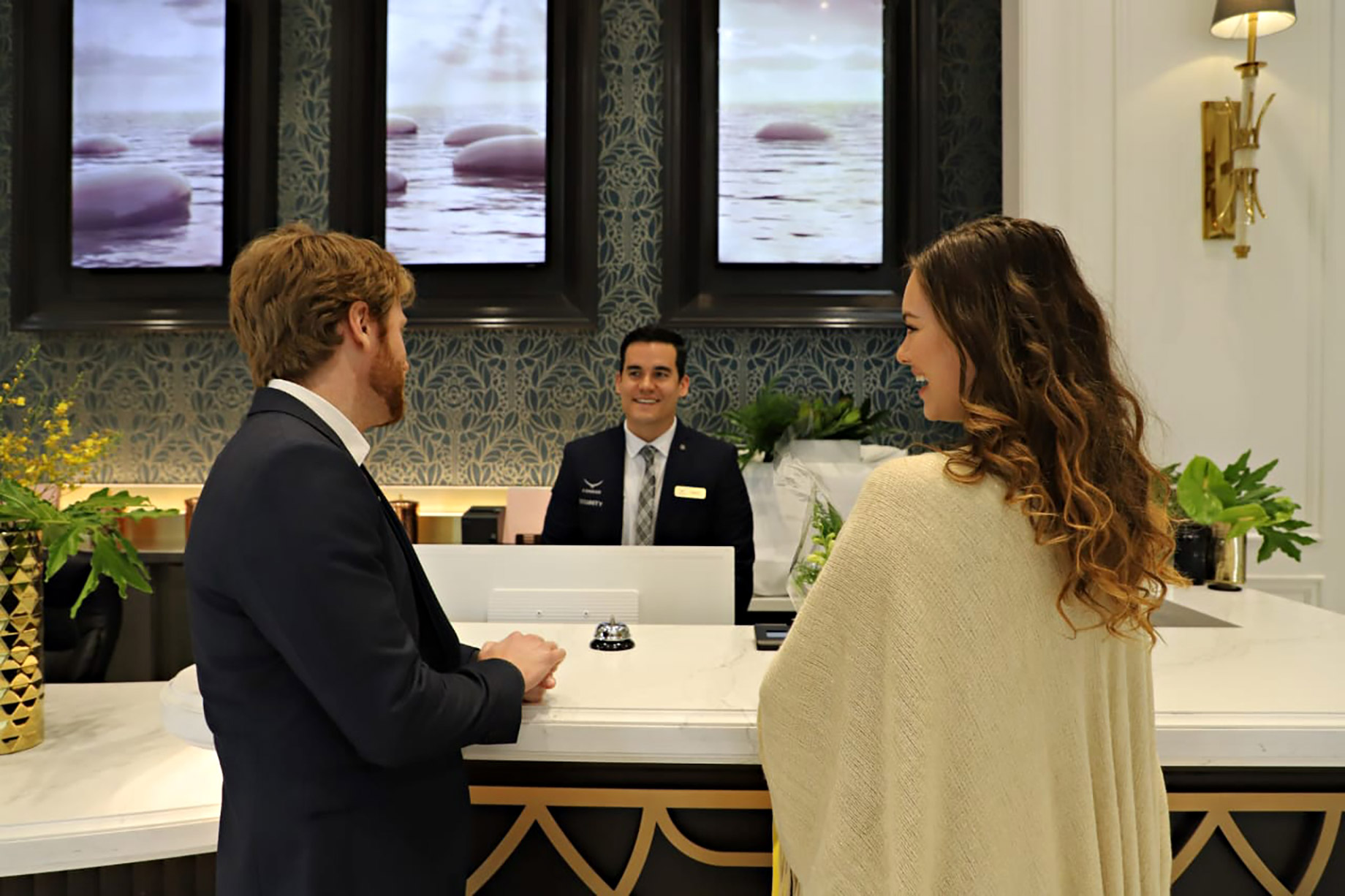A Condor Security concierge professional engaging warmly with residents at a high-end front desk, illustrating the fusion of premium security and five-star hospitality.