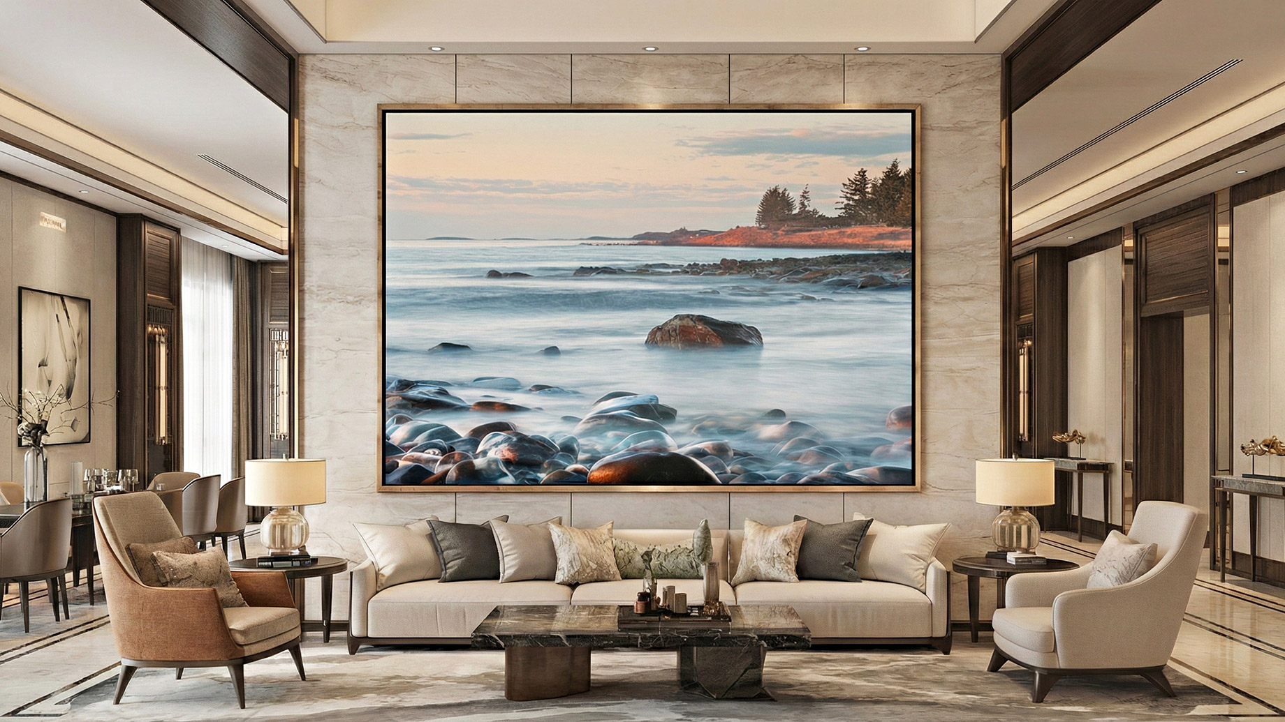 A sophisticated luxury living room featuring a massive, framed seascape photograph as the central architectural element. The artwork, depicting a serene rocky coastline at twilight, anchors the room's neutral color palette and hangs above a modern beige sofa, illustrating how large-scale wall art creates a focal point in high-end real estate.