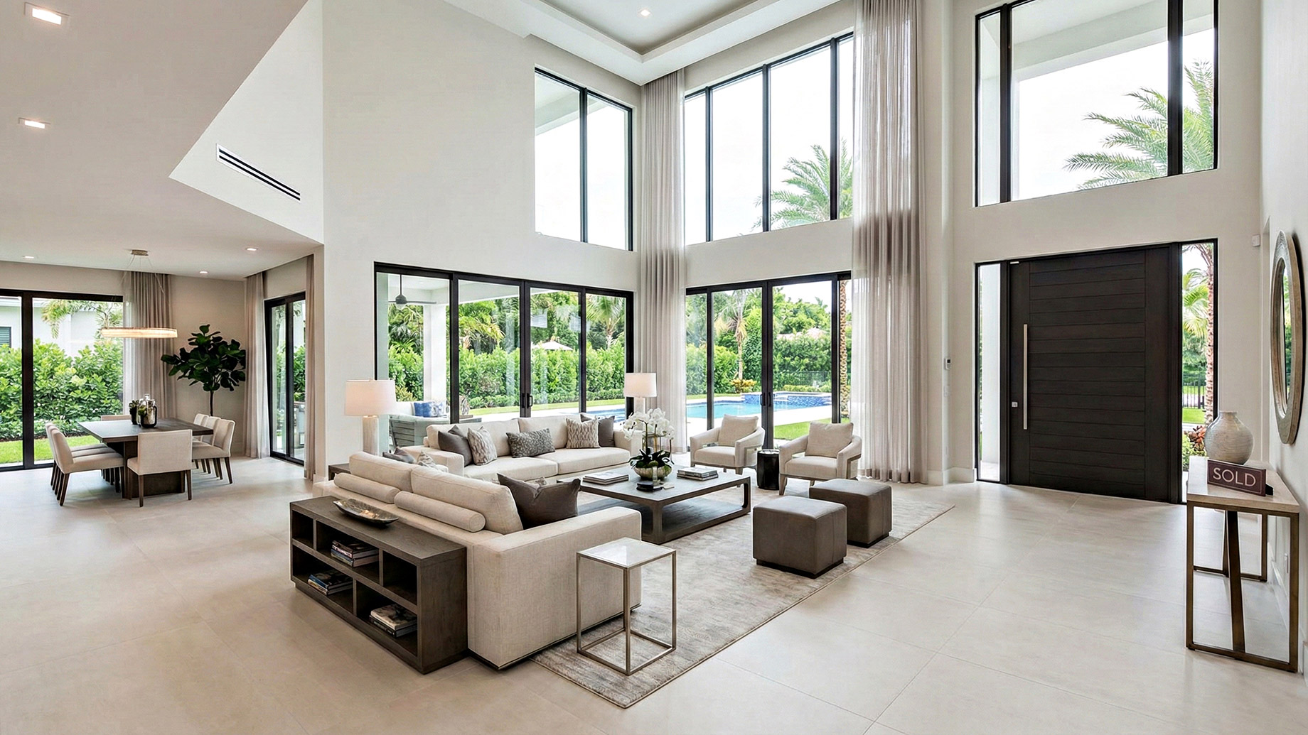 A spacious luxury living room featuring high ceilings, floor-to-ceiling windows, and clean neutral furniture, demonstrating a perfectly staged home ready for a quick sale.