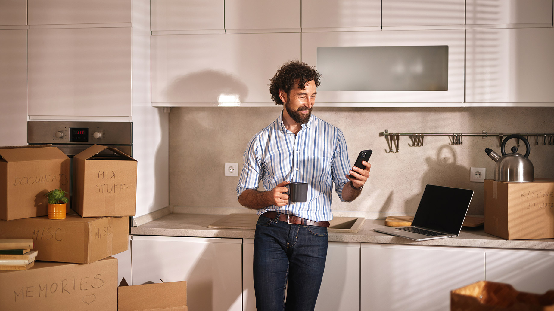 A Man Stands in a Bright Kitchen Filled With Moving Boxes