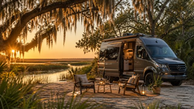 Luxury camper van parked beside a peaceful Charleston marsh at sunset with Spanish moss, outdoor chairs, lanterns, and an upscale off-grid campsite.