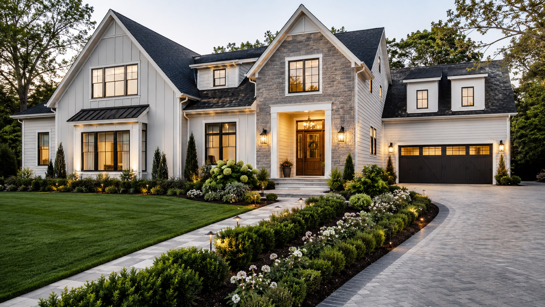 Luxury modern farmhouse exterior with premium siding, stone accents, manicured landscaping, walkway lighting, and a welcoming front entry.